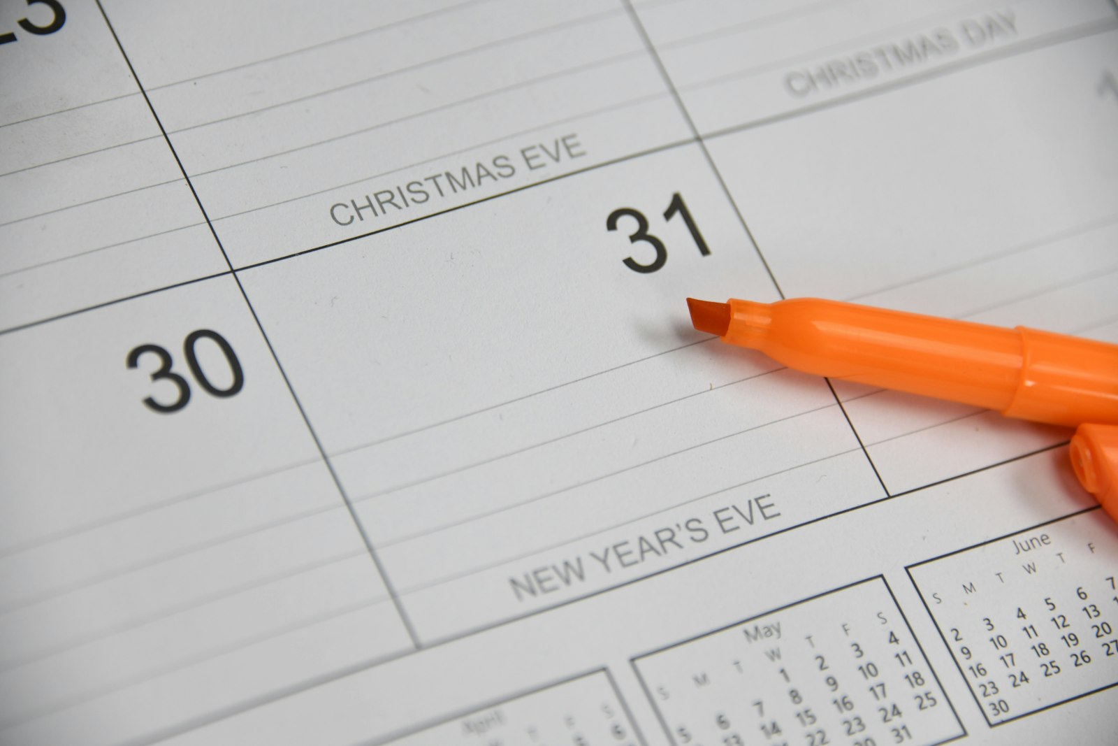 A calendar open at the end of December, with Christmas Eve, Christmas Day and New Year's Eve marked and a highlighter resting on the thirty-first.